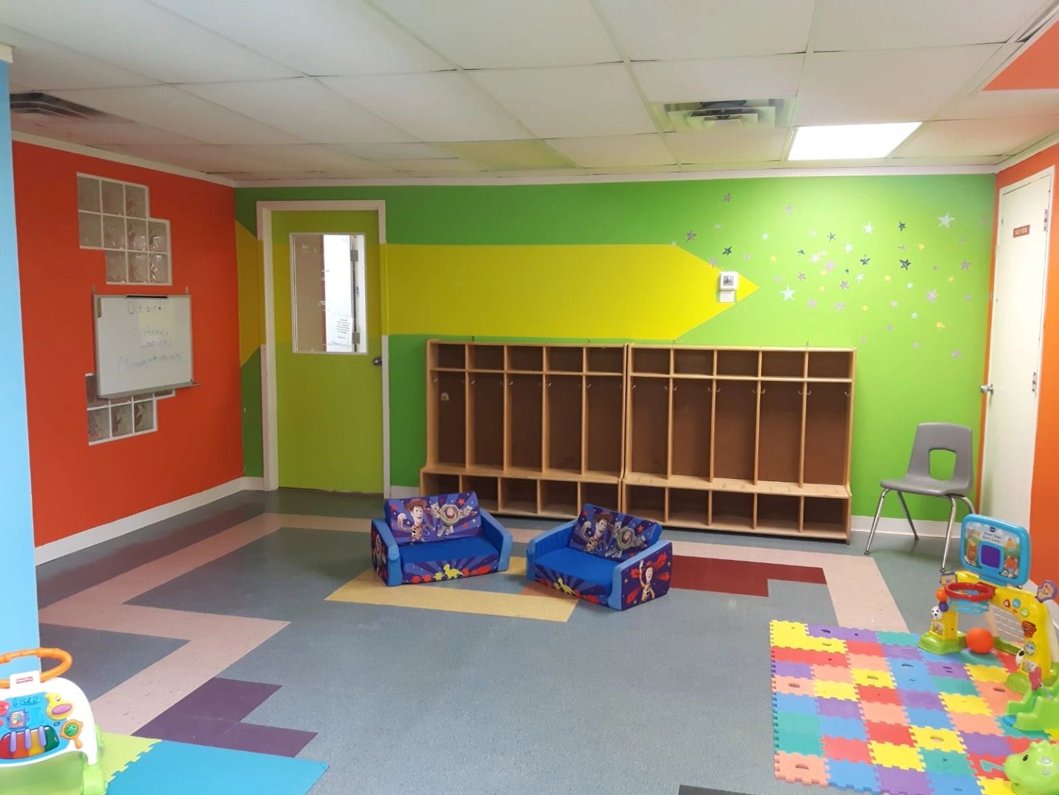 Kanata playroom with colourful floor mats, child-sized seats and open cubbies.
